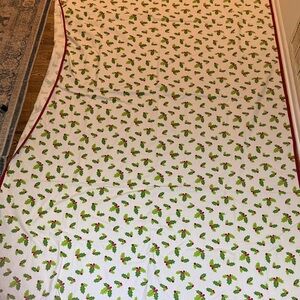 Gently used cream colored table cloth with holly theme and red trim.